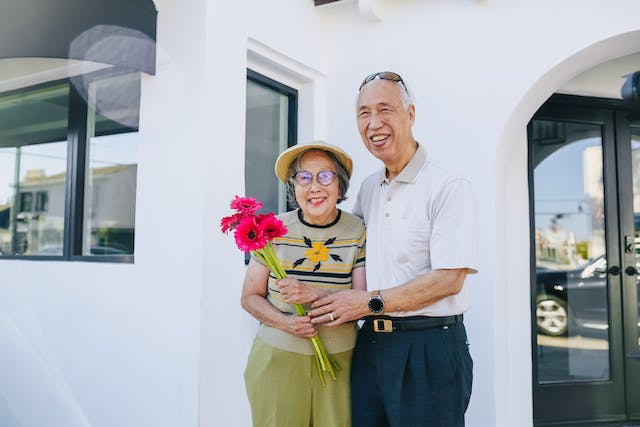 Retired married couple in front of paid off home